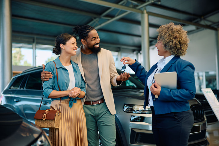 Young couple receiving car keys from car broker