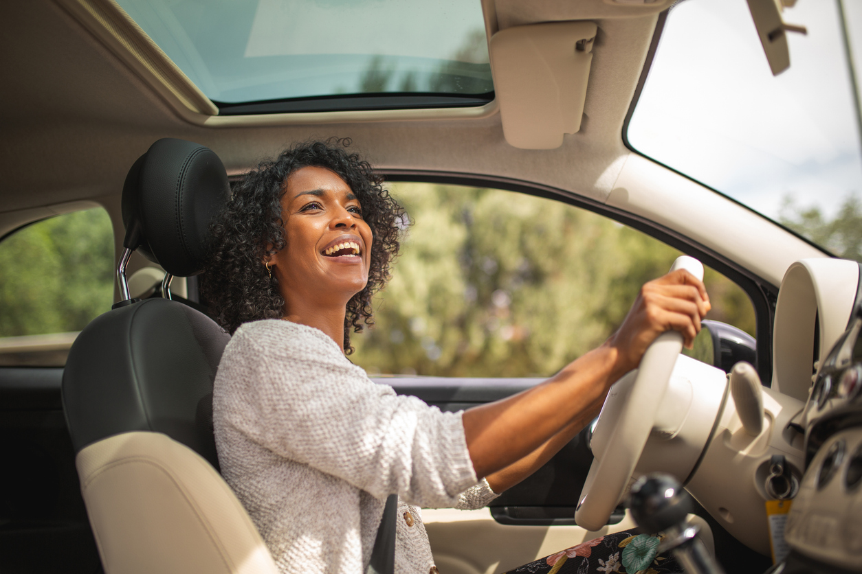 Portrait smiling young african american woman driving car
